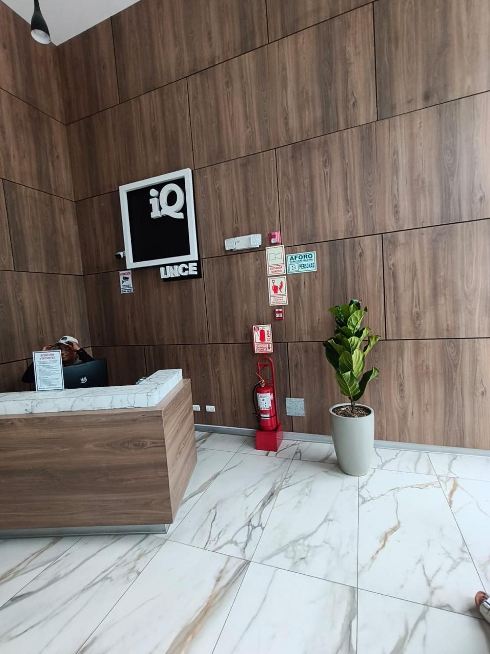 An interior space featuring a modern showroom with large ceramic tiles and bright lighting. The walls display brand signage and various tile samples. A sleek, minimalist desk is centered, surrounded by a clean and spacious environment.
